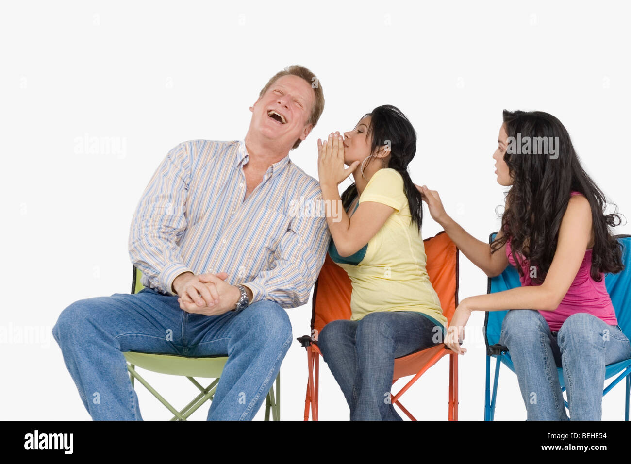 Giovane donna whispering in suo padre l orecchio con sua sorella tirando i capelli Foto Stock