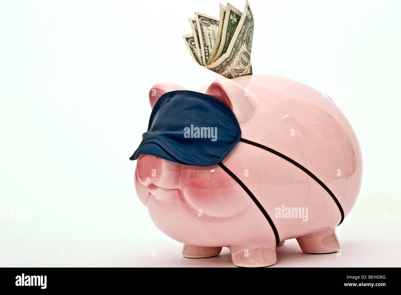 Salvadanaio con le fatture del dollaro nella slot di moneta che indossa una maschera di sospensione Foto Stock