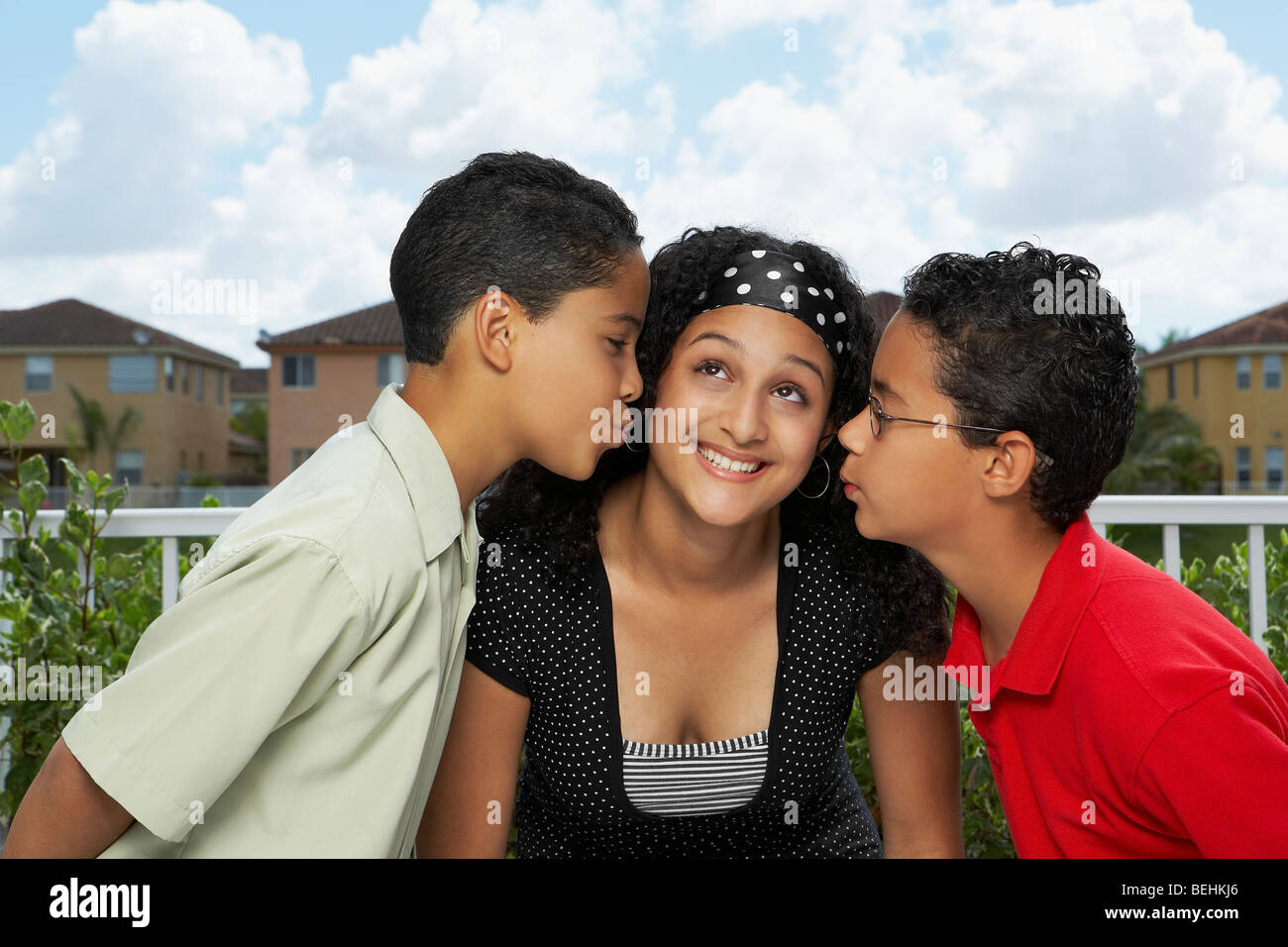 Il profilo laterale di due ragazzi baciare una ragazza adolescente Foto Stock