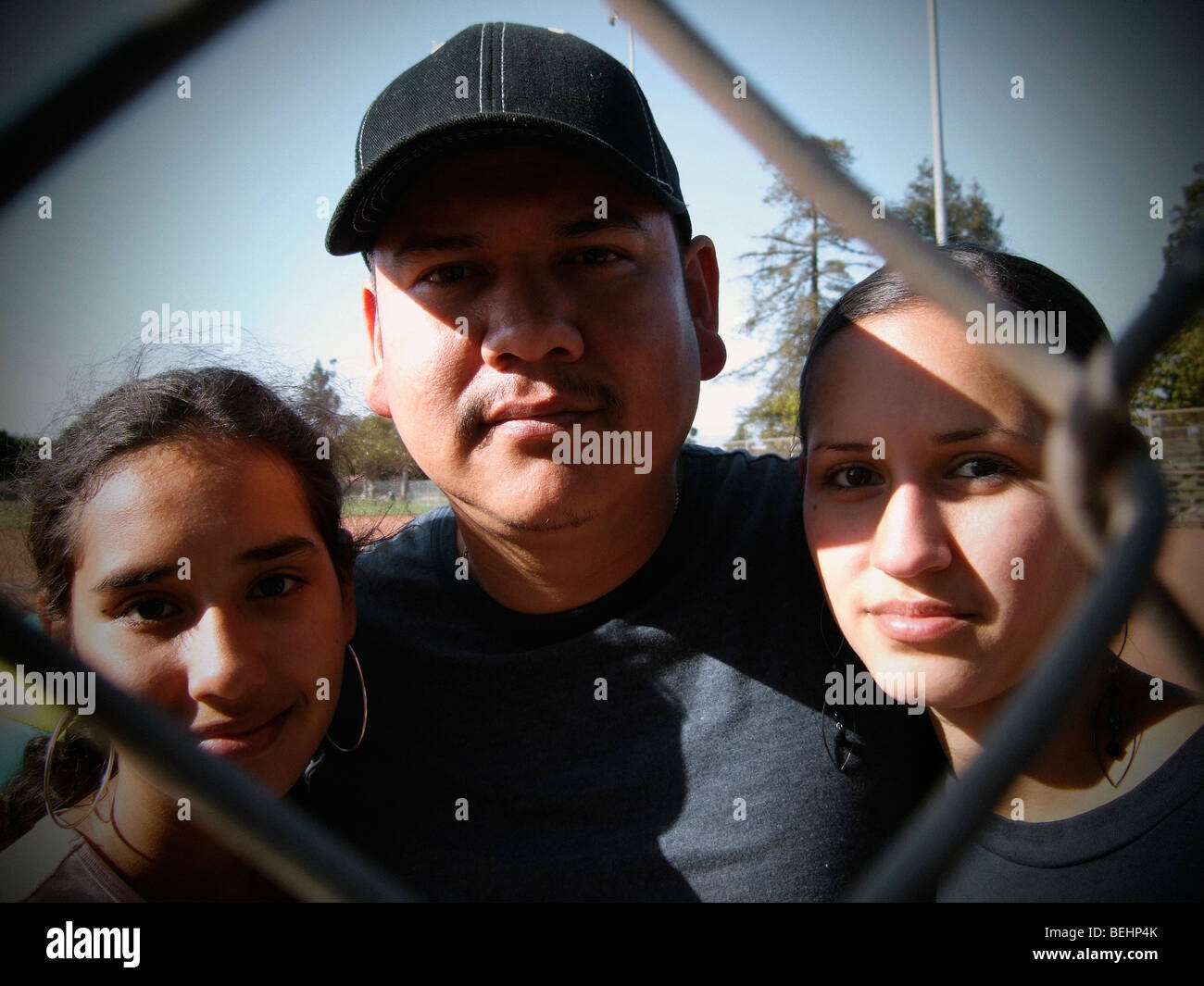 Padre di due figlie guardando attraverso la recinzione di baseball Foto Stock