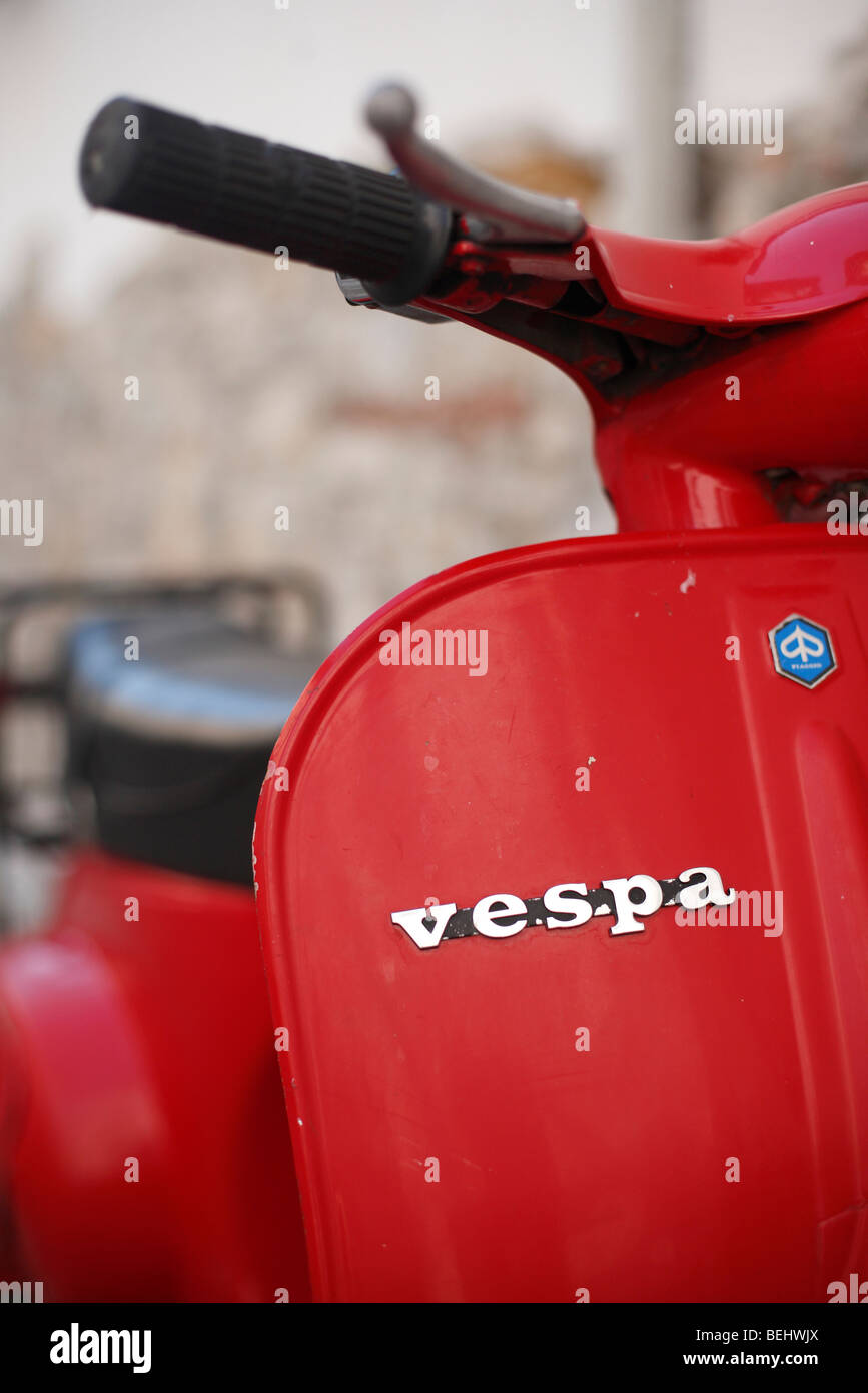 Un rosso scooter Vespa contro un muro di pietra Foto Stock