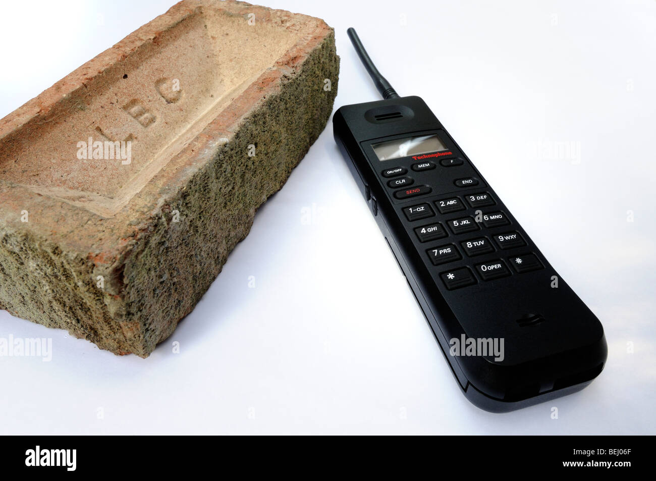 In mattoni e grande vecchio nero telefono cellulare su sfondo bianco Foto Stock