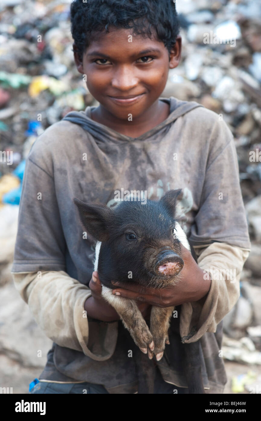 Casta inferiore ragazzo indiano con piccole maiale in una discarica. Andhra Pradesh, India Foto Stock