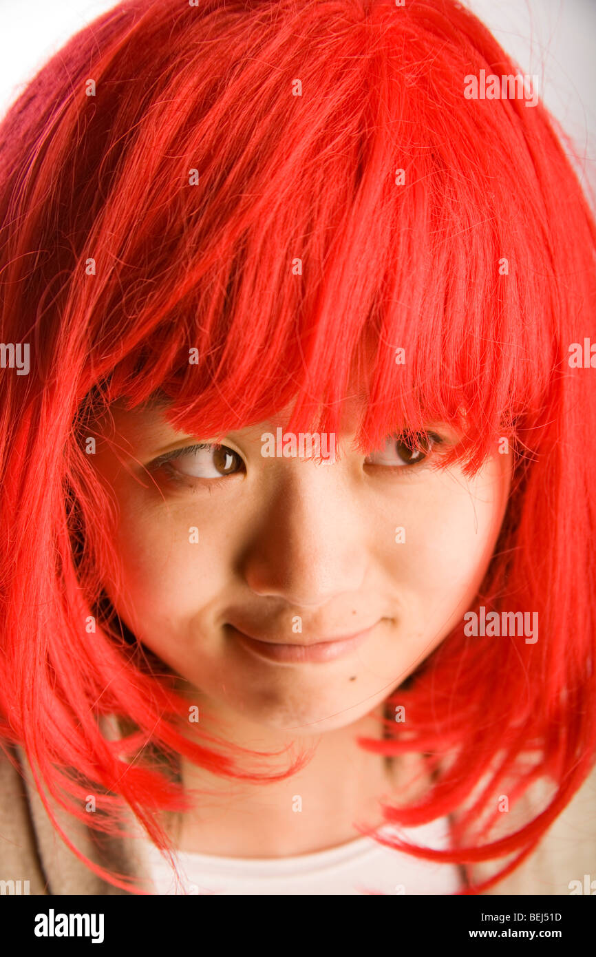 Giovane ragazza cinese vestito in un colore rosso brillante parrucca per un po' di divertimento. Foto Stock