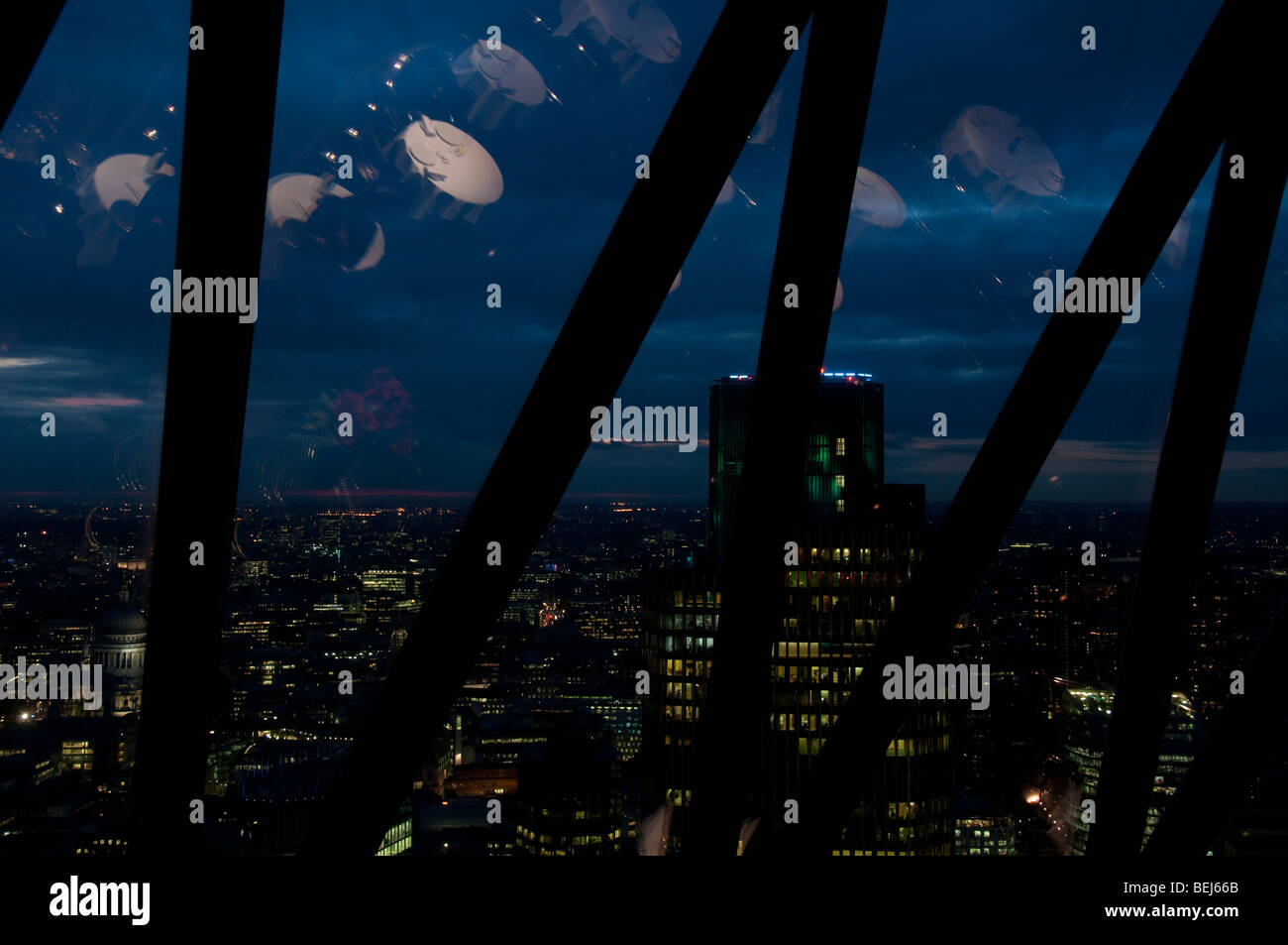 Città di Londra di notte come si vede dalla barra, 30 St Mary Axe, il Gherkin, Londra. Le riflessioni di tavole di ristorante in Windows Foto Stock