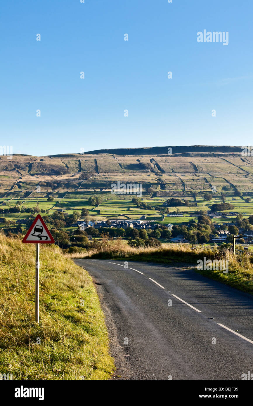 Strada tortuosa Yorkshire Dales England Regno Unito con un cartello di segnalazione per lo slittamento Foto Stock