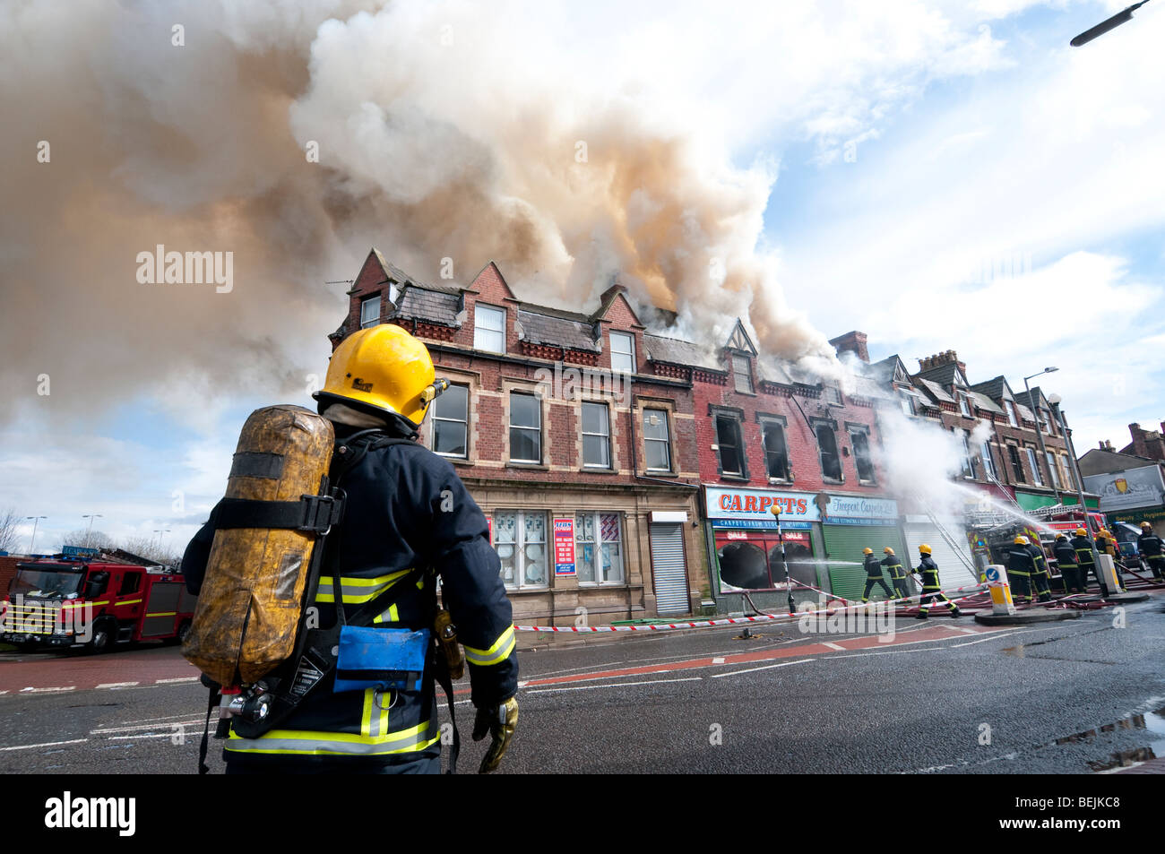 Firefighers e apparecchio a scena di incendio di grandi dimensioni con il fumo nero Foto Stock