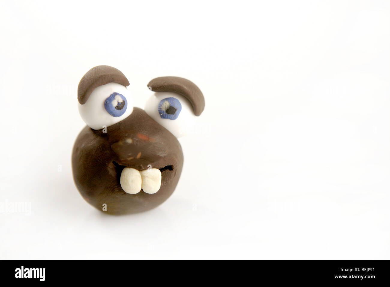 Divertente faccia giocattolo artigianale di plastilina, grandi denti e gli occhi su bianco Foto Stock