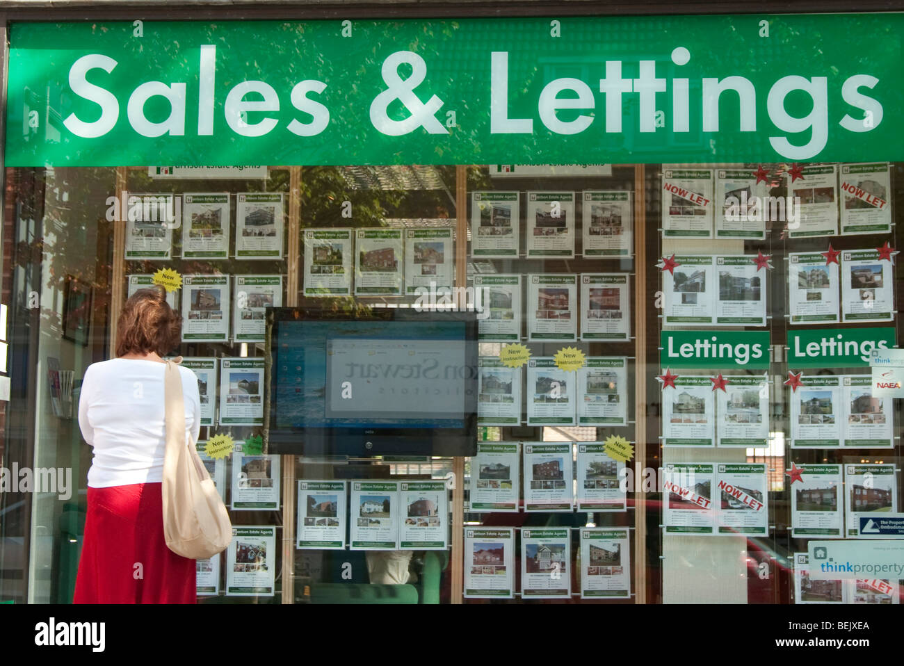 Donna che guarda in agenti immobiliari finestra Foto Stock