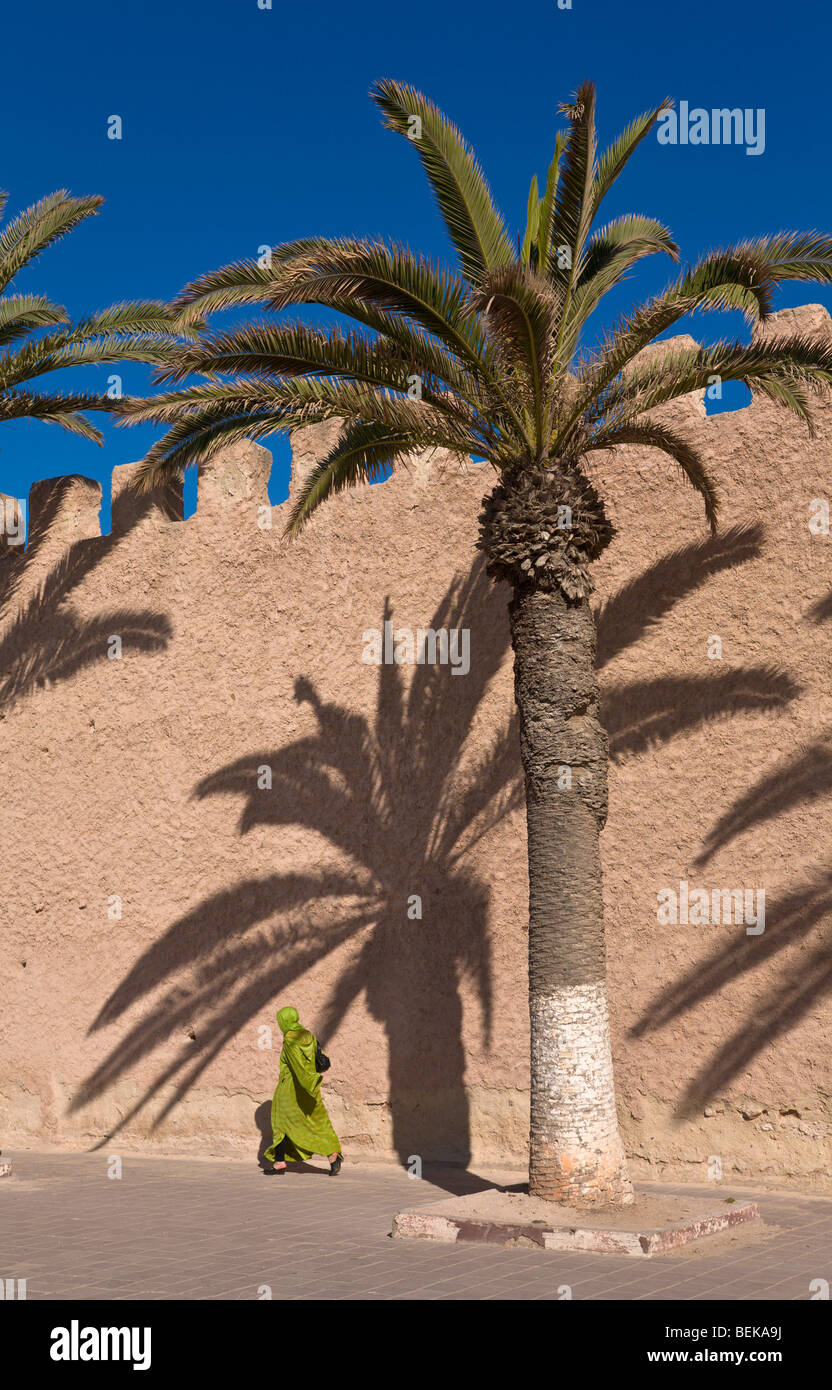 Donna locale camminando accanto alla cinta muraria della città essaouira marocco Foto Stock