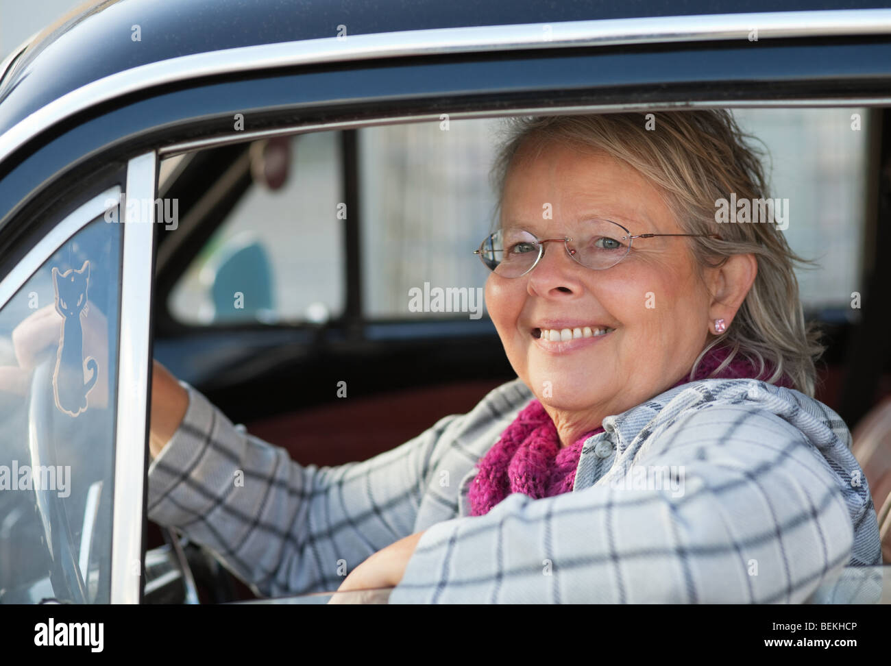 Felice senior donna alla guida di un'auto oldtimer Foto Stock