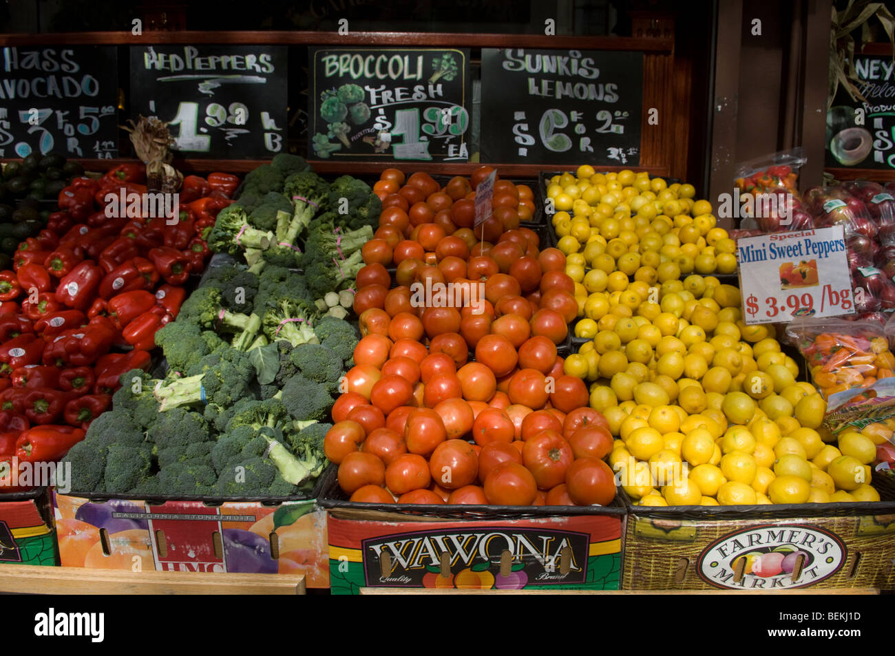 Peperoni rossi, broccoli, i pomodori e i limoni in vendita al di fuori di un negozio di alimentari in New York Foto Stock