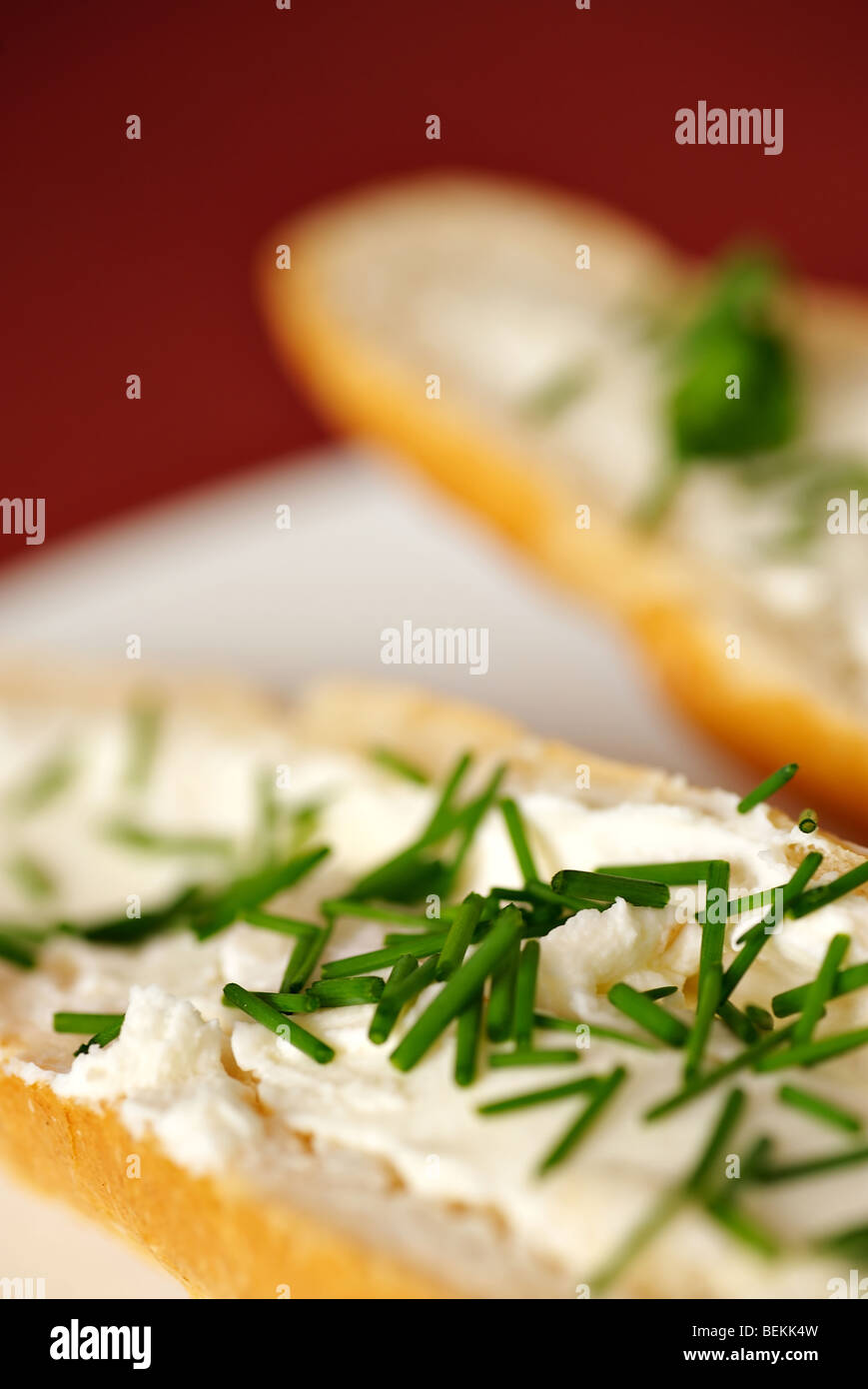 Close up dettaglio di pane con formaggio e erba cipollina, shallow DOF, rosso - sfondo viola, piastra bianca, composizione verticale Foto Stock