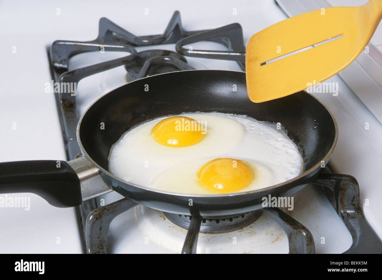 Due uova sunny side fino circa ottenere ribaltato dalla spatola giallo in padella antiaderente Foto Stock
