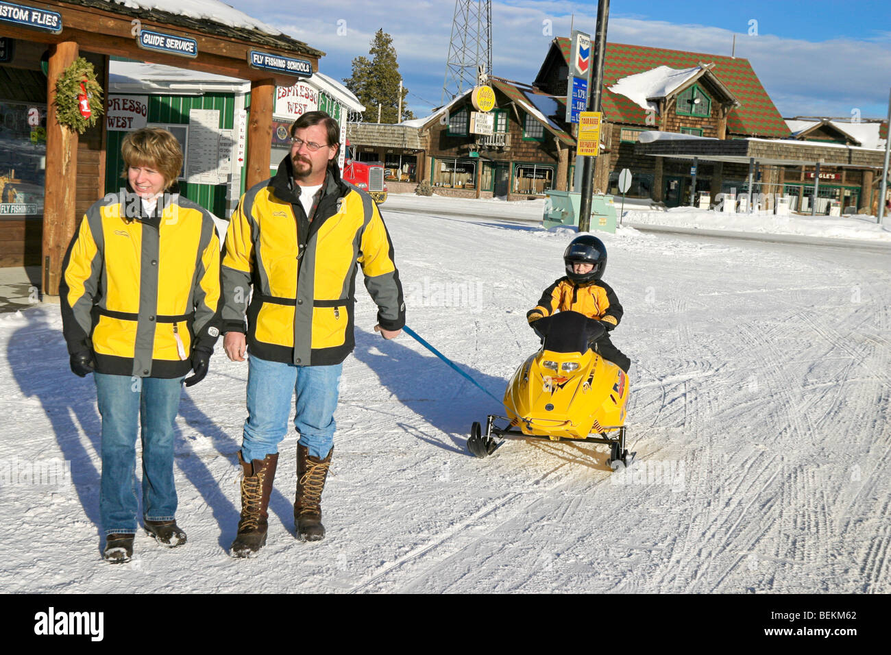 Famiglia locale si spegne per una passeggiata in West Yellowstone, Montana durante l'inverno, il traino il loro figlio su un mini motoslitta Foto Stock