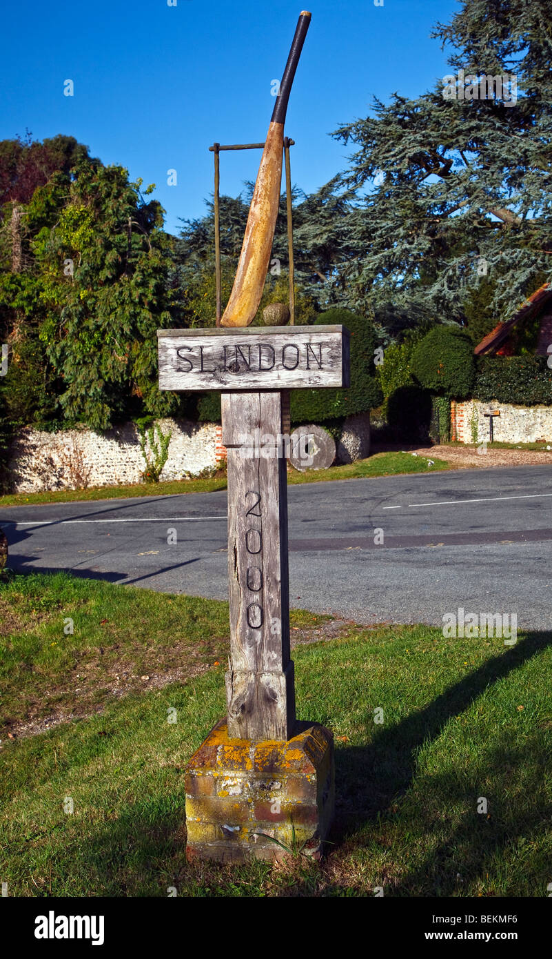 Un segno di villaggio con un legno scolpito cricket bat e palla appoggiata contro un paletto Slindon, West Sussex, in Inghilterra, Regno Unito 2009 Foto Stock