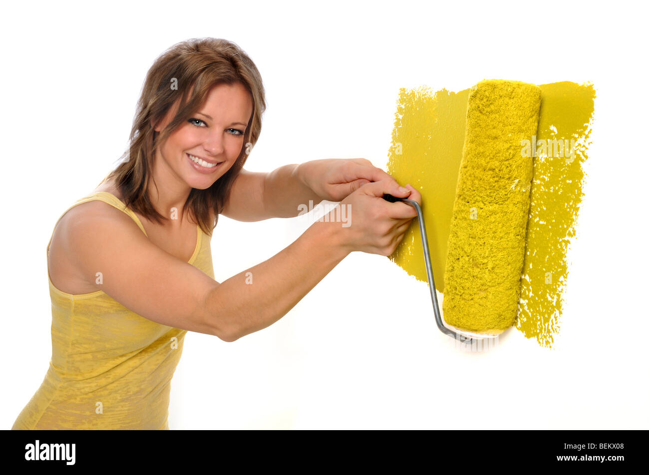 Bella donna usando il rullo di vernice di colore giallo Foto Stock