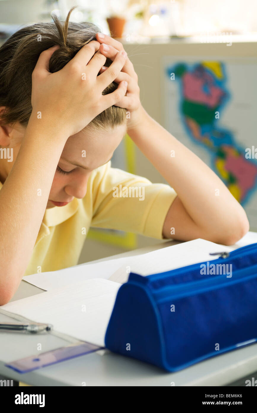 Ragazzo seduto alla scrivania con testa in mani Foto Stock
