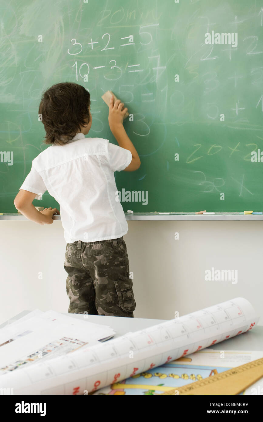 Ragazzo la cancellazione di lavagna, vista posteriore Foto Stock