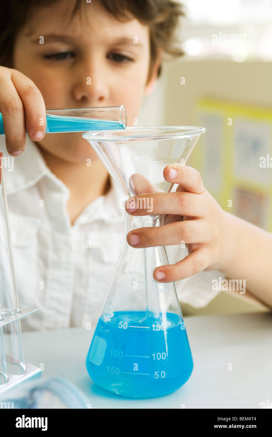 Ragazzo trasferire il liquido dal tubo di prova a bicchiere mediante imbuto Foto Stock