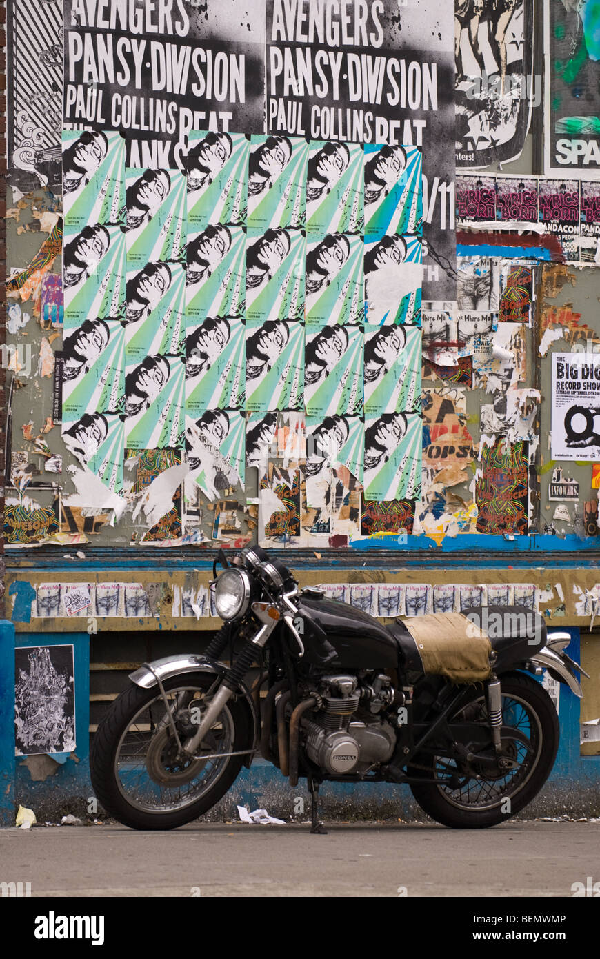 Un motociclo su una strada adornata con manifesti in Seattle, WA. Foto Stock