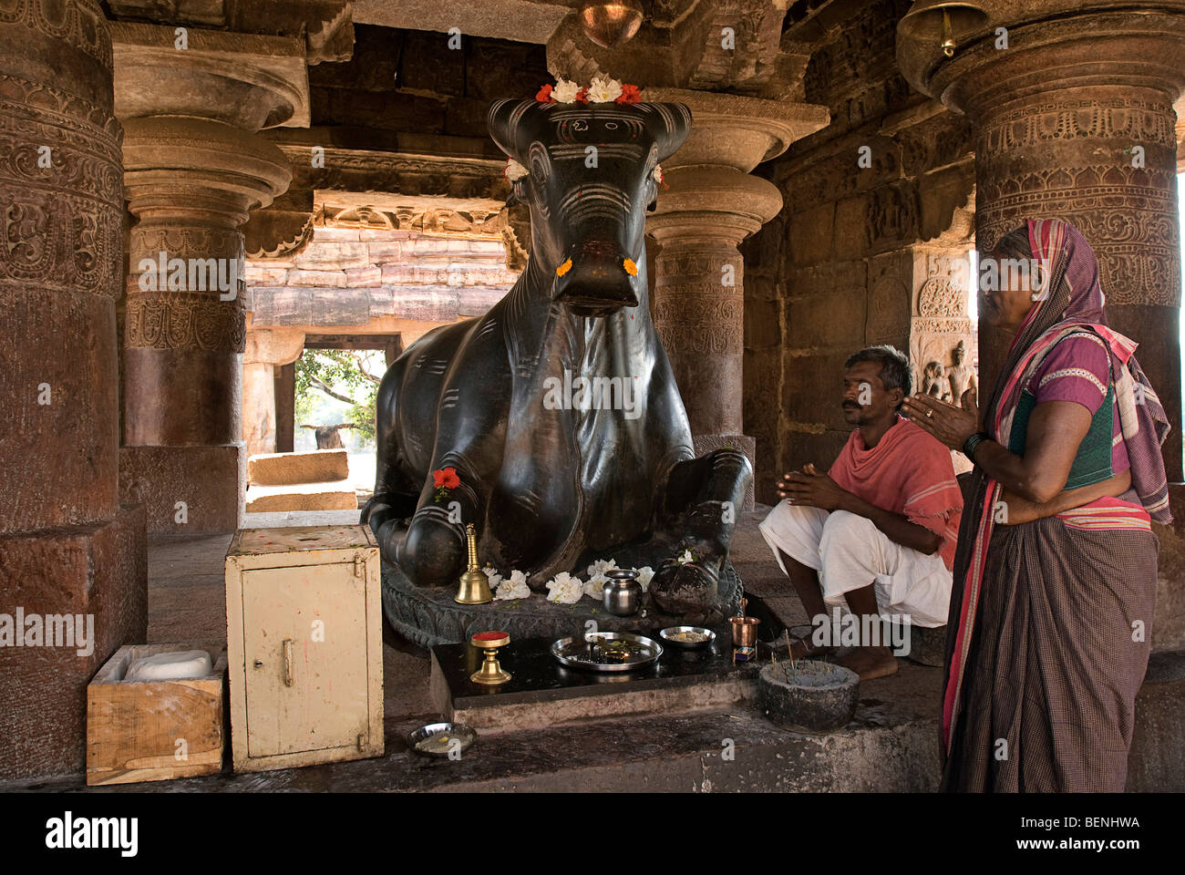 Un uomo e una donna in adorazione il monolito Nandi Statua in Nandi Mandapa Pattadakal Karnataka India Foto Stock
