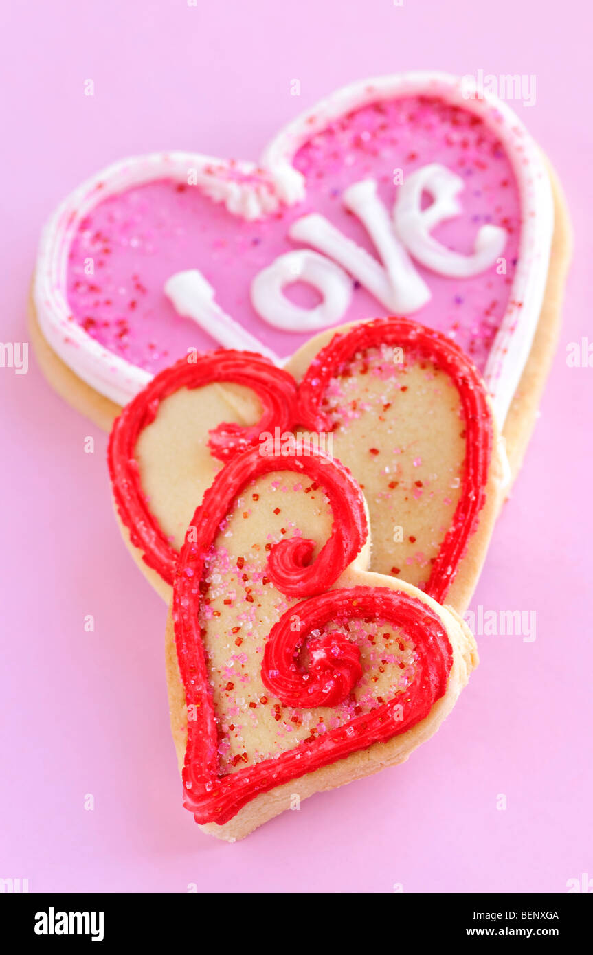 In casa cotto frollini biscotti di San Valentino con glassa su sfondo rosa Foto Stock
