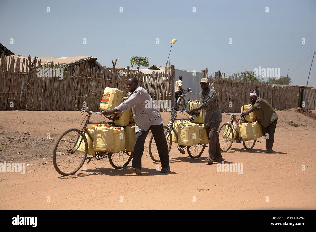 Il SUD SUDAN Street scene a Juba. Gli uomini che trasportano i bidoni riempiti con acqua che essi hanno raccolto dal fiume Nilo. Foto Stock