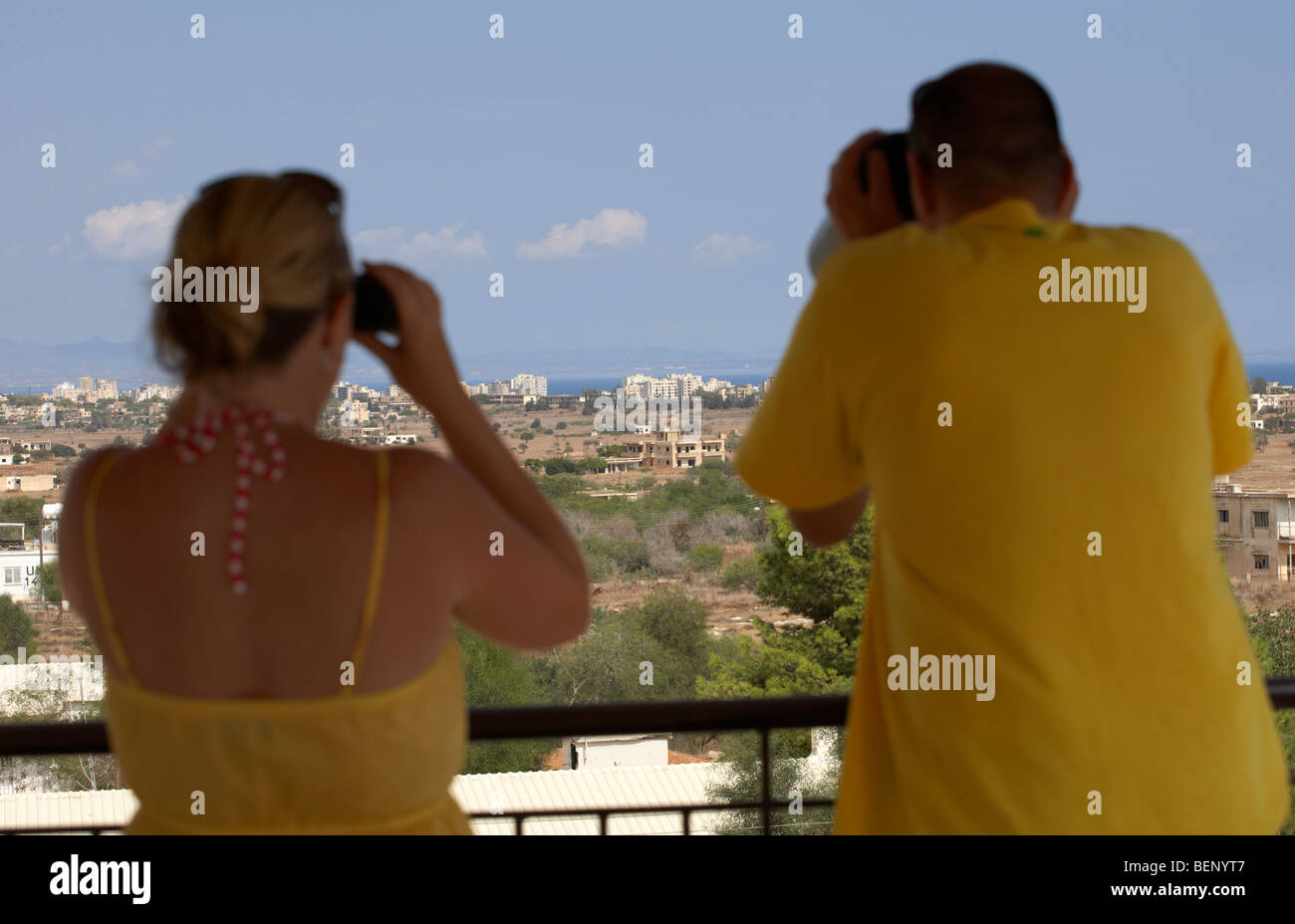 Turista giovane utilizzando il binocolo a trascurare l'ONU zona di buffer nel verde della linea che divide il nord e il sud di Cipro a Famagosta Foto Stock