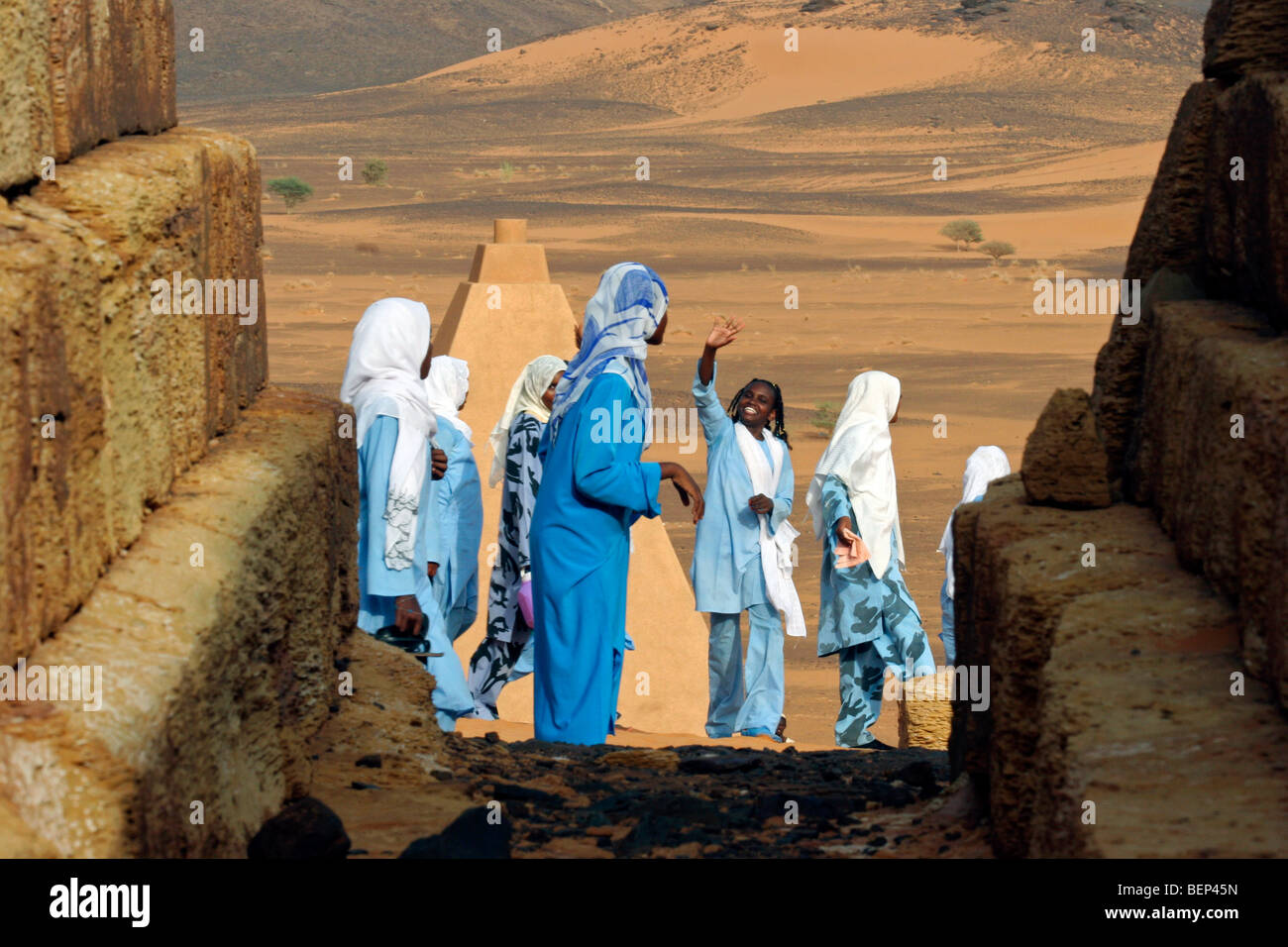 Giovani donne vestite di tobes e hijabs visitando le piramidi di Meroe nel deserto del Sahara, Sudan, Nord Africa Foto Stock