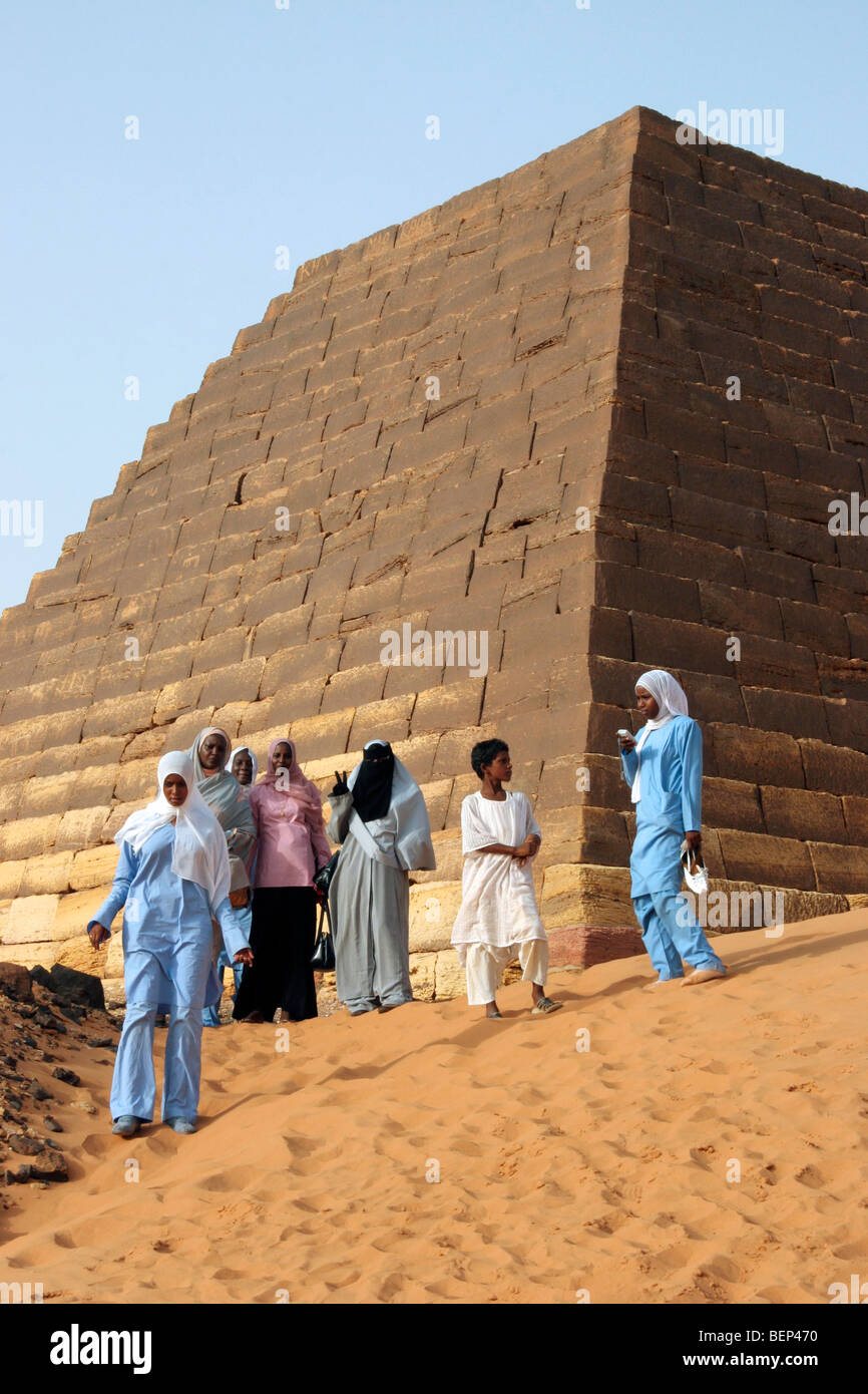 Giovani donne vestite di tobes e hijabs visitando le piramidi di Meroe nel Deserto Nubiano, Sudan, Nord Africa Foto Stock