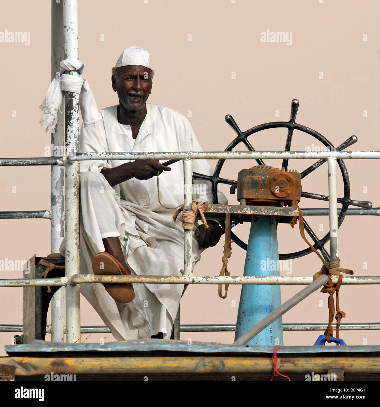 Capitano vestito di bianco thawb / / thobe dishdasha al volante di ferry boat, Sudan, Nord Africa Foto Stock