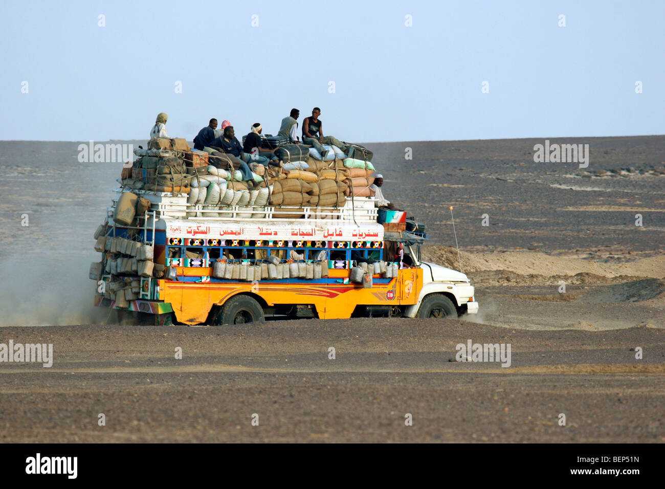 Fortemente caricato il bus con i bagagli e i passeggeri sul tetto di guida attraverso il deserto del Sahara in Sudan, in Africa del Nord Foto Stock