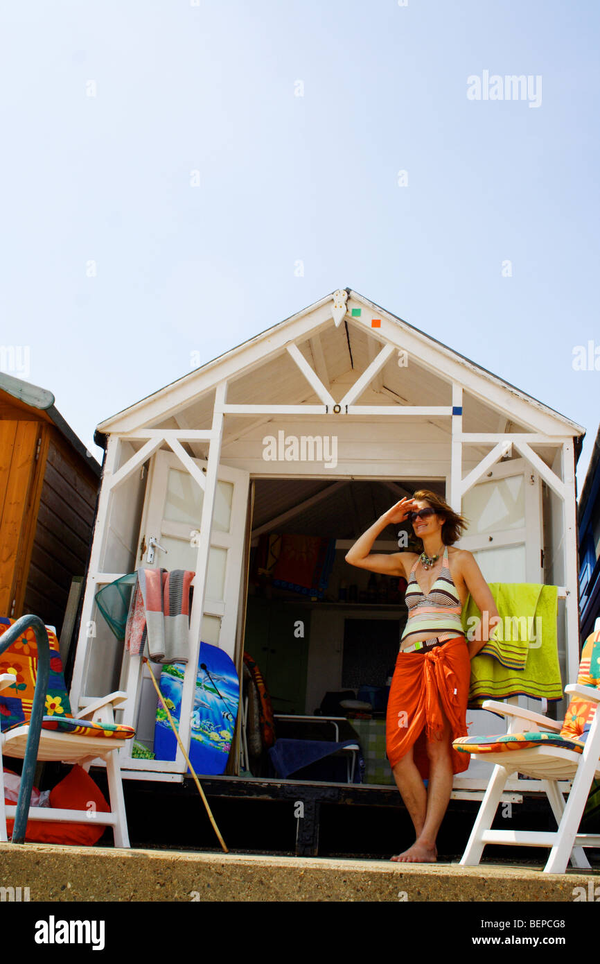 Donna in piedi al di fuori di un inglese beach hut su un inglese un giorno d'estate Foto Stock