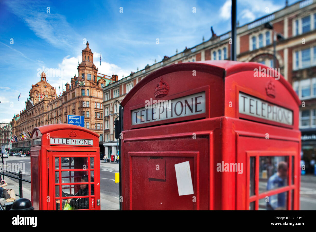 Tipico cabine telefoniche rosse su Brompton Road con Harrods edificio sullo sfondo. London, England, Regno Unito Foto Stock