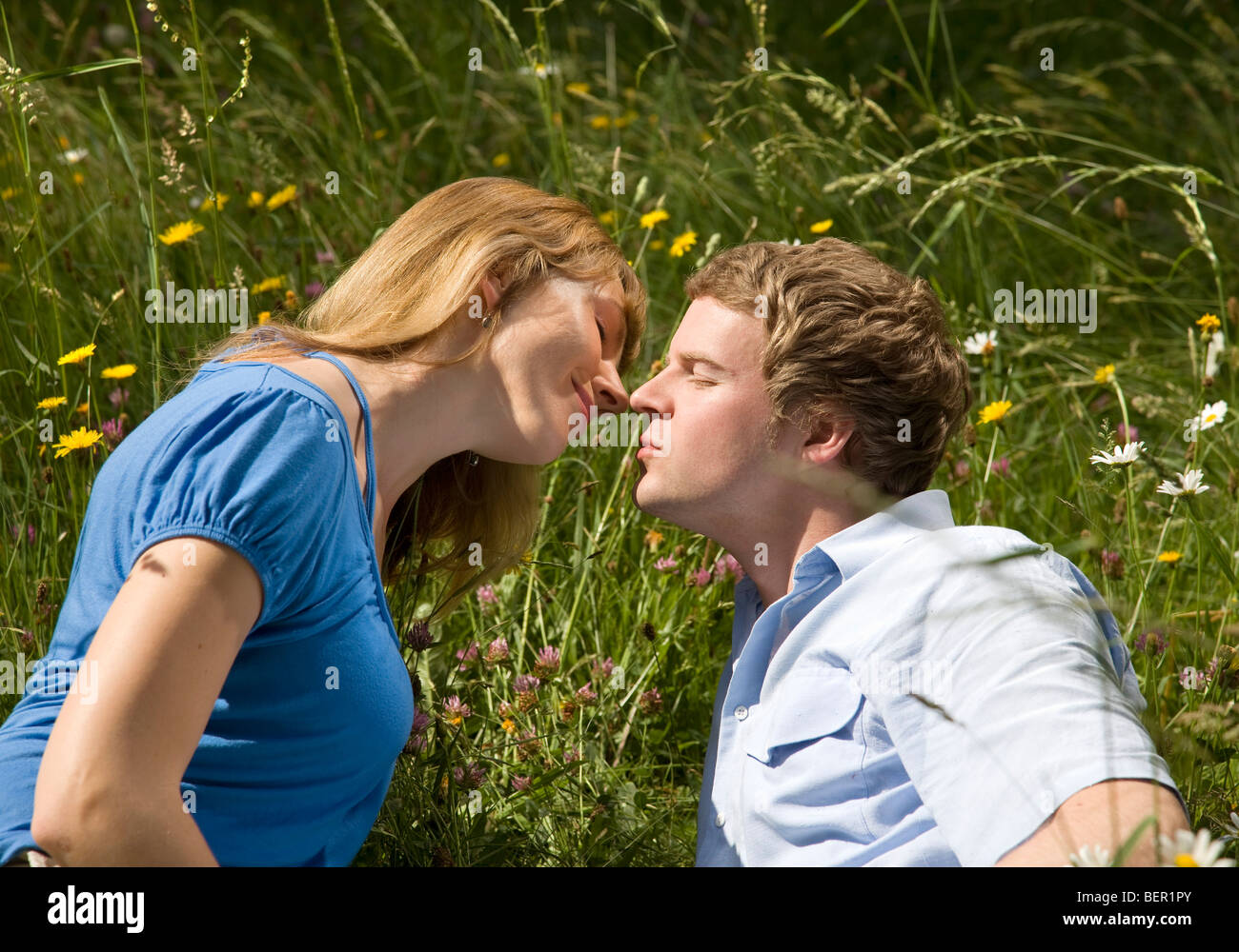 Uomo Donna baciare in erba con fiori Foto Stock
