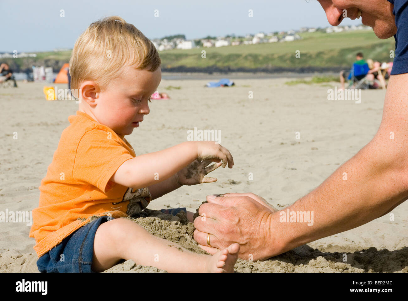 Little Boy Toddler giocando nella sabbia con suo padre in spiaggia, Poppit Sands, Galles Foto Stock