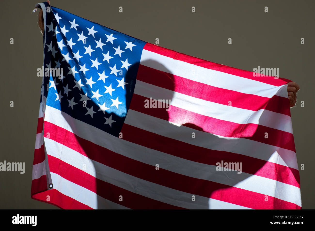 Uomo di drappeggio bandiera americana sulla parete Foto Stock