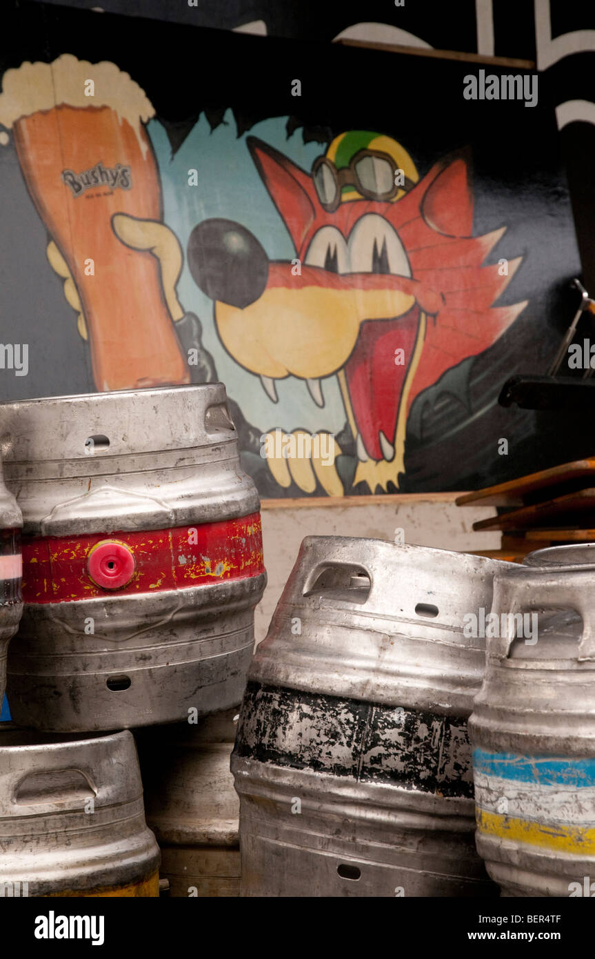 Un cespuglioso birreria del dipinto di segno visibile dietro una pila di colorati botte di birra presso la birreria nell'Isola di Man. Foto Stock