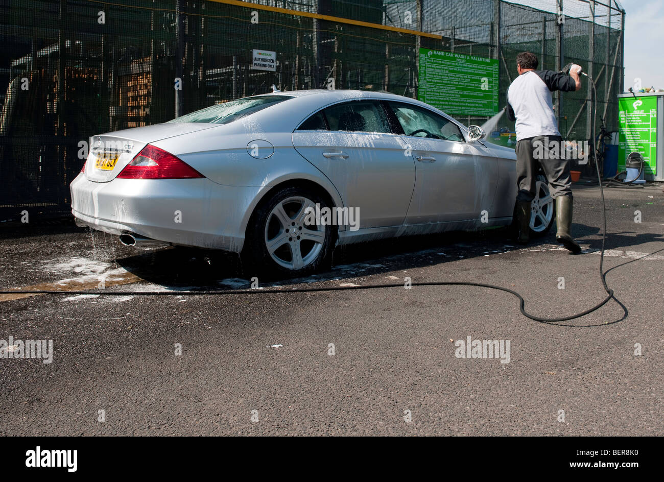 Europeo orientale immigrati operando una mano Servizio di lavaggio auto nel parcheggio di un supermercato / negozio fai-da-te nel SW di Londra. Foto Stock