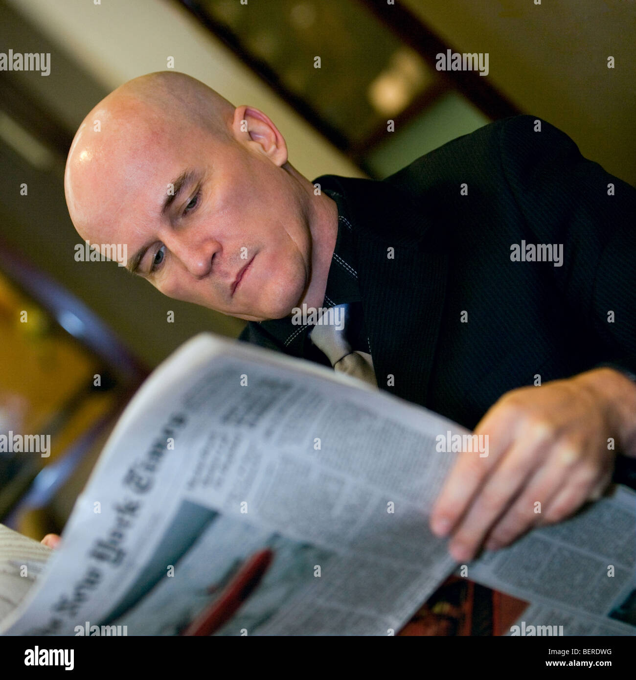 Ritratto di un uomo calvo nel suo late 40's indossando un abito scuro leggendo un giornale. Foto Stock