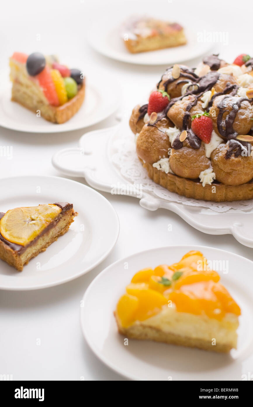 Pezzi di torta intorno a crostata con bignè e fragola, sfondo bianco Foto Stock