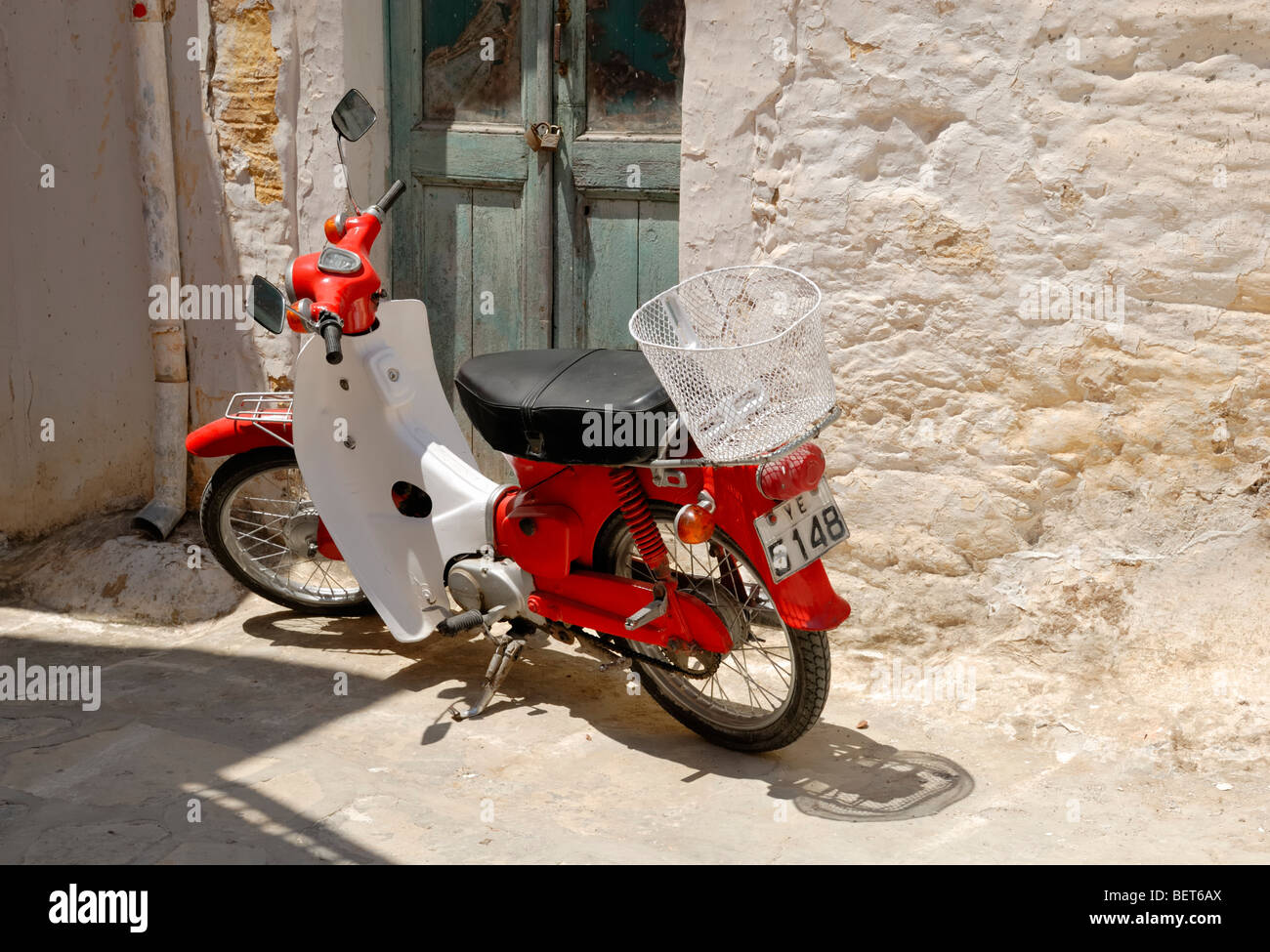 Un vecchio rosso scooter parcheggiato nel vicolo nel cuore del piccolo villaggio storico di Halki. Halki, Tragaea, Isola di Naxos, ... Foto Stock