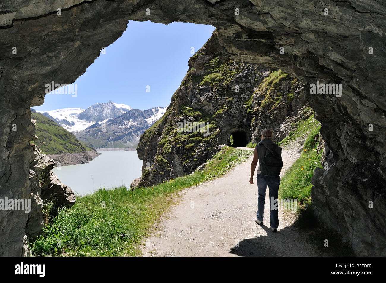 Passeggiate turistiche attraverso la grotta lungo il Lac des Dix, formato dalla grande diga di Dixence in Valais / Wallis, alpi svizzere, Svizzera Foto Stock