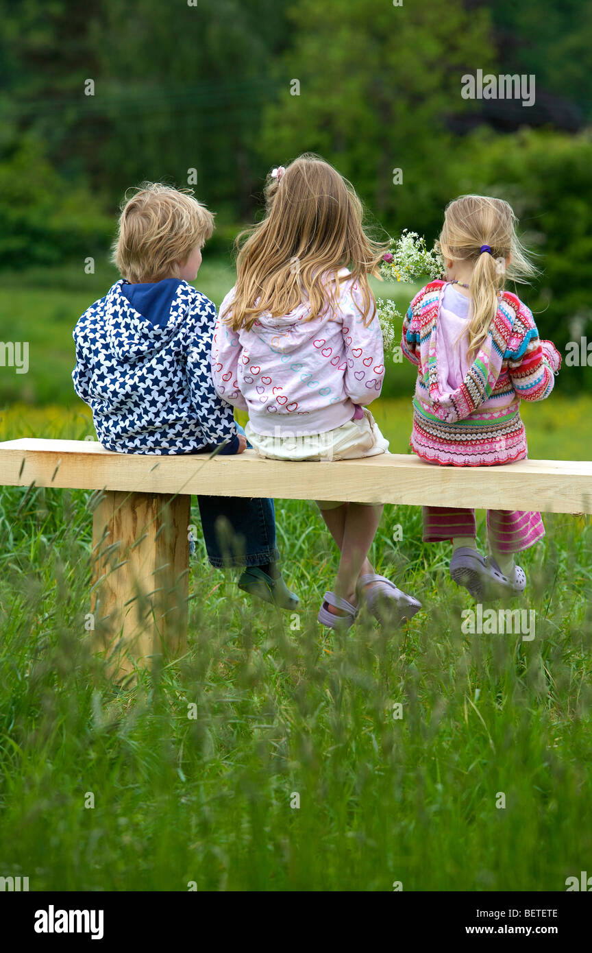 3 bambini seduti su una panchina. Foto Stock