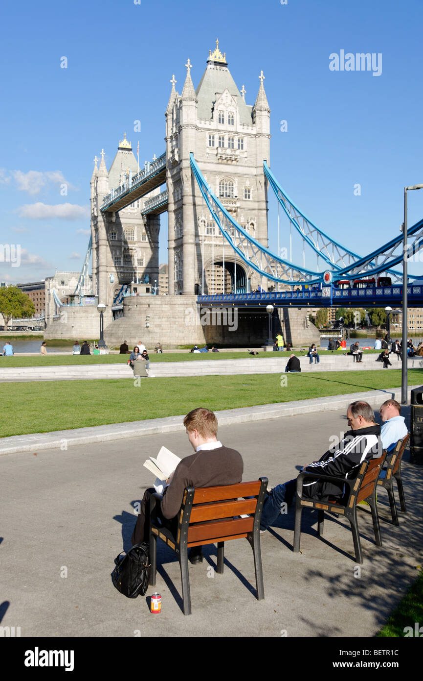 L'uomo della lettura in Potters Fields Park nella parte anteriore del Tower Bridge. Londra. La Gran Bretagna. Regno Unito Foto Stock