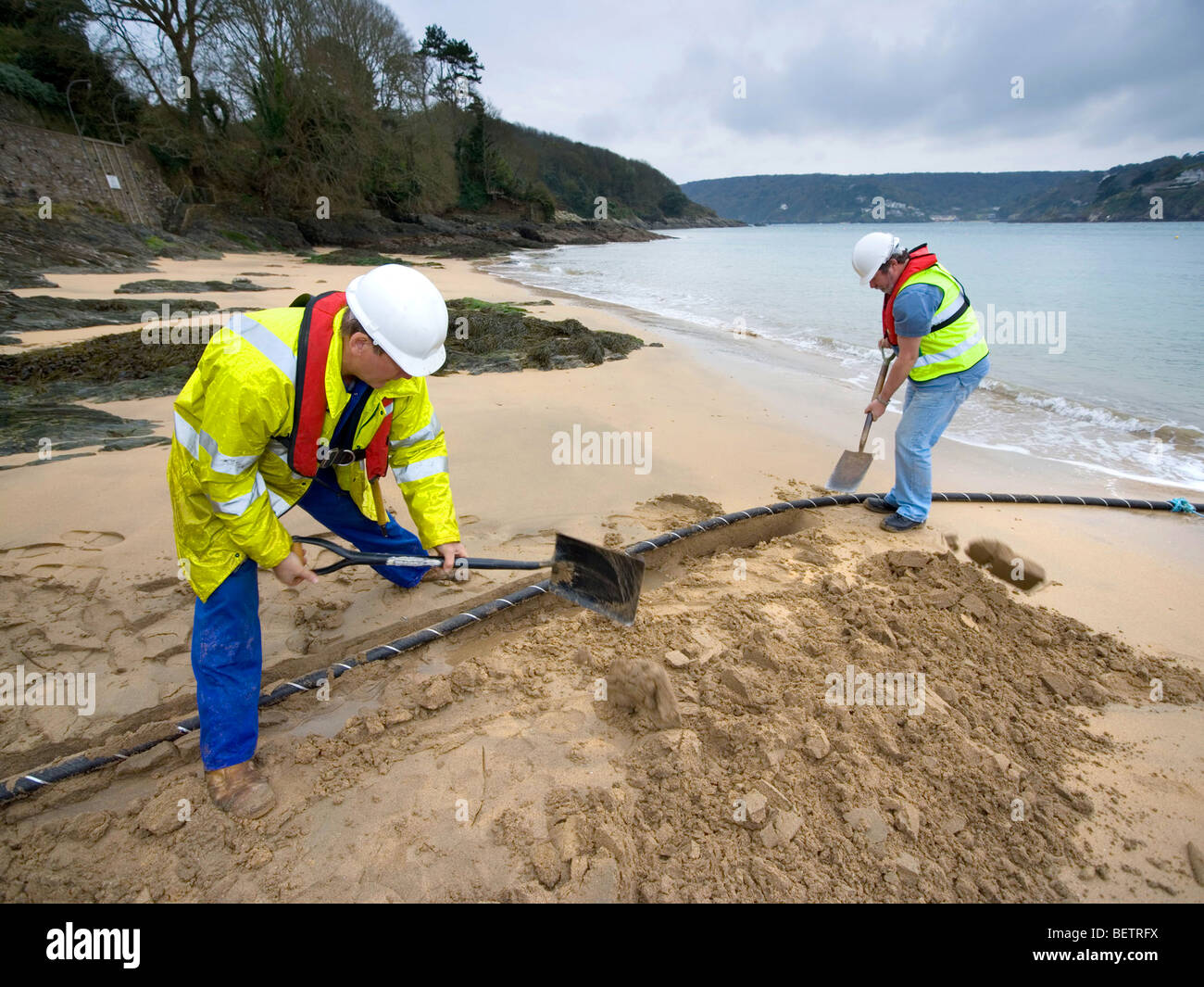 I lavoratori di seppellimento di un nuovo cavi telefonici di rame su una spiaggia vicino a Salcombe in Devon Foto Stock