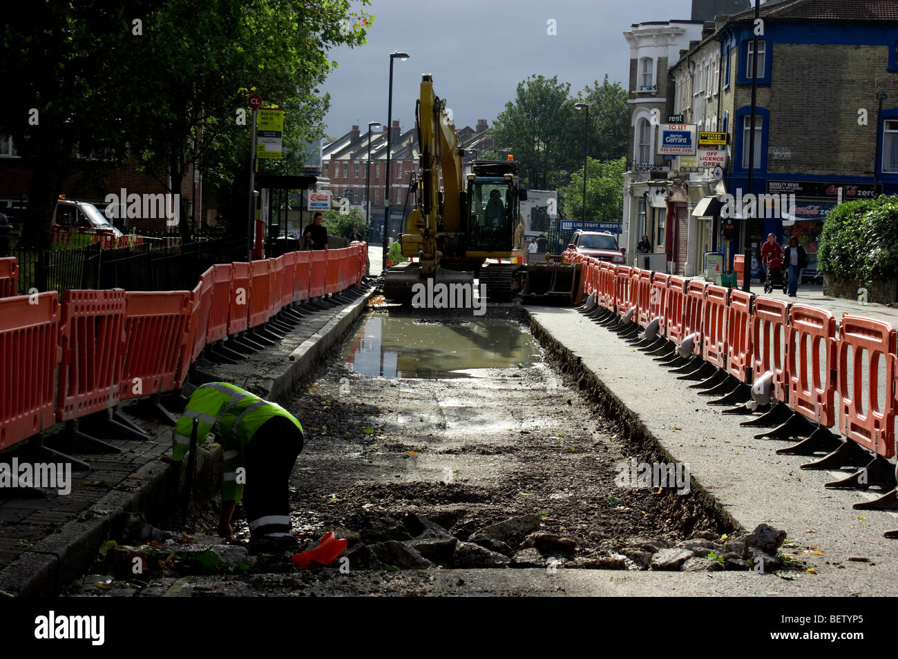 Cat digger in Crouch Hill , Londra Nord visto in uso resurfacing la strada presso la fermata del bus area. Foto Stock