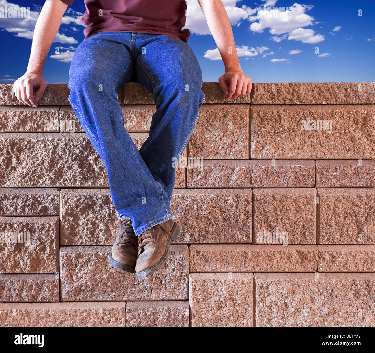 Uomo in jeans blu seduti all'aperto su un muro di mattoni Foto stock - Alamy