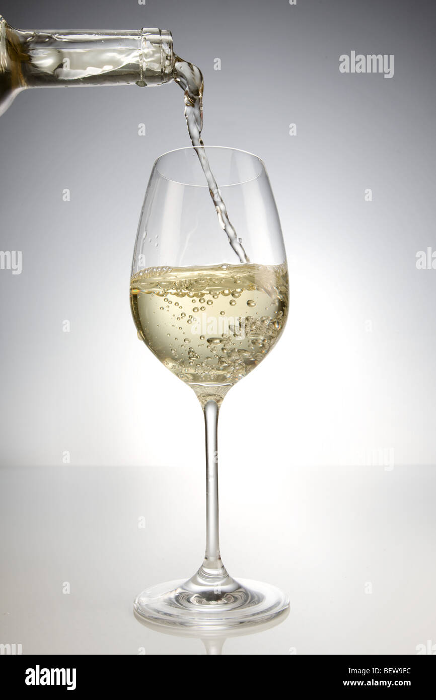 Versare il vino bianco in un bicchiere, close-up Foto Stock
